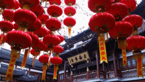 Rote chinesische Laternen mit goldenen Quasten und Schriftbannern vor einem traditionellen Gebäude in Shanghai.